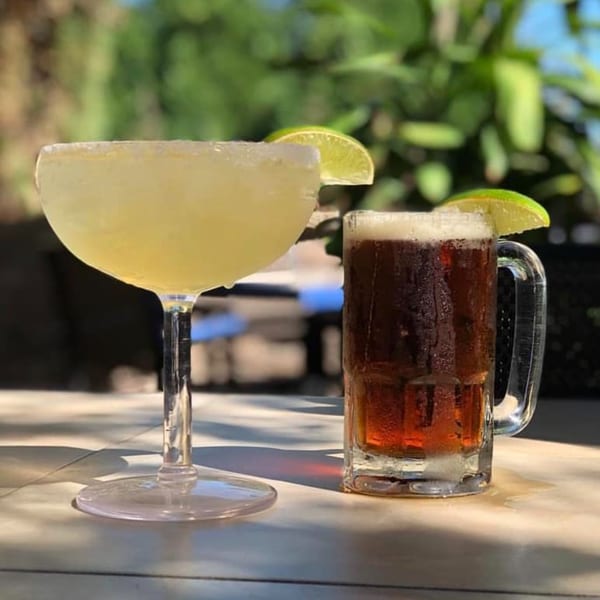 A Coyoacan Mexican Restaurant margarita and a dark beer with lime on an outdoor table.