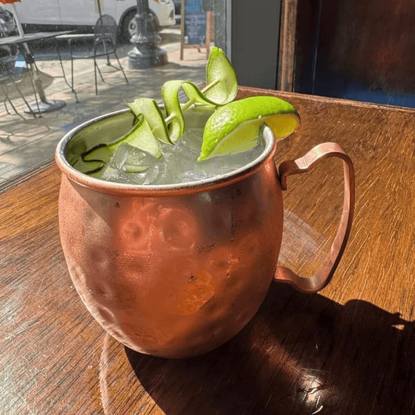 A copper mug filled with a Coyoacan Mexican Restaurant cocktail, ice, cucumber ribbons, and lime.