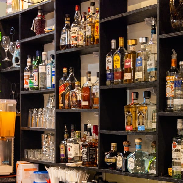 A well-stocked bar shelf at Coyoacan Mexican Restaurant, featuring various tequila, whiskey, and liquor bottles.
